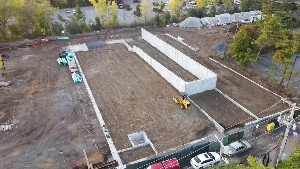 Wide-angle aerial shot of Avalon Quincy construction site with precast foundation walls and utility installations
